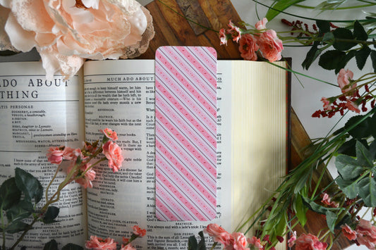 Bookmark with illustrations of candy sprinkles and diagonal lines and stripes in varying shades of pink.