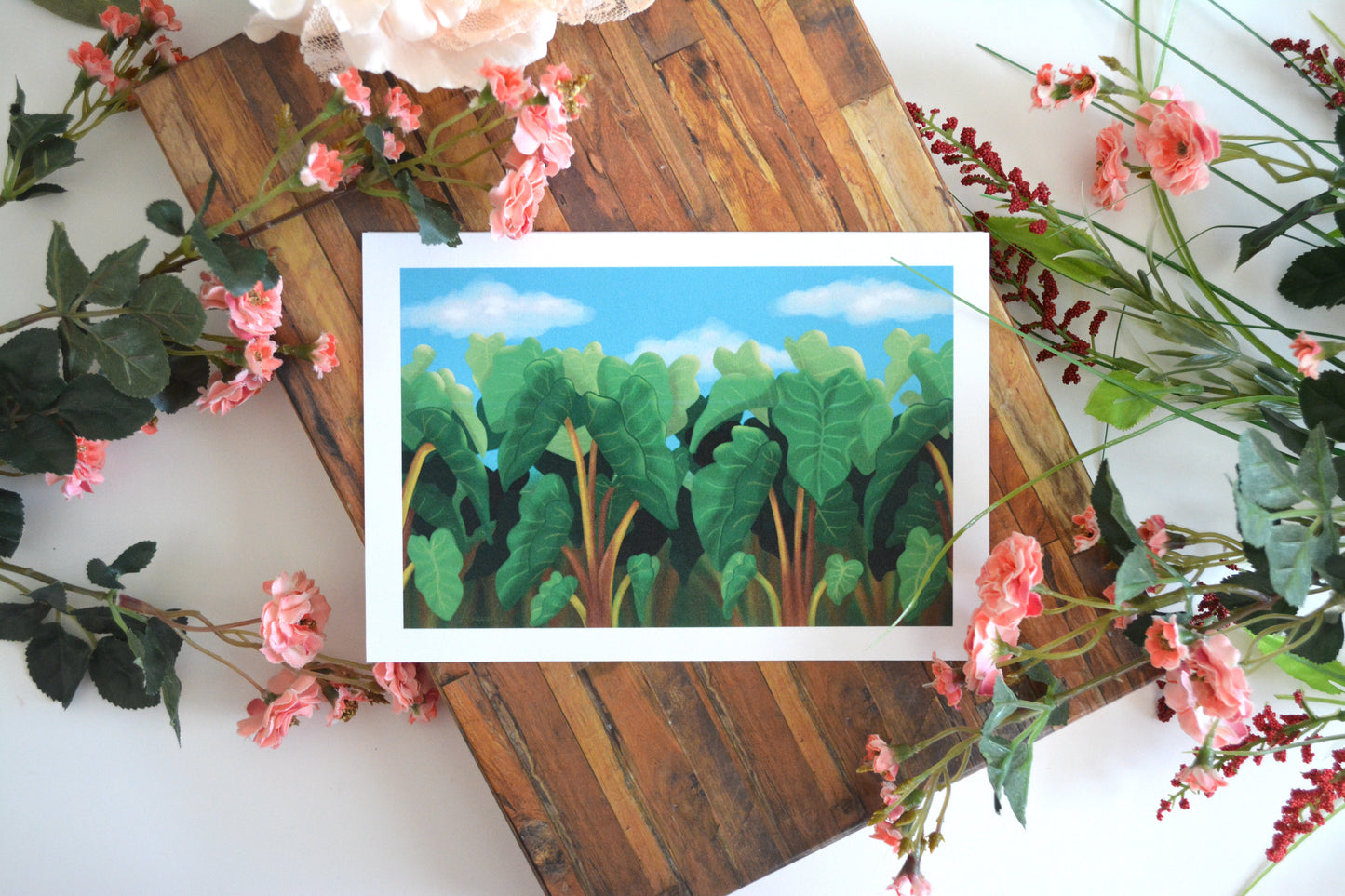 Art print with illustration of lush Hawaiian kalo (taro) plants in front of a bright blue sky.