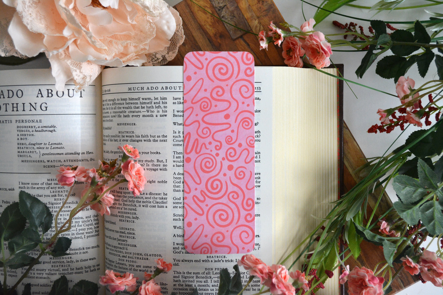 Bookmark with dark pink icing drizzle swirls on a light pink background.