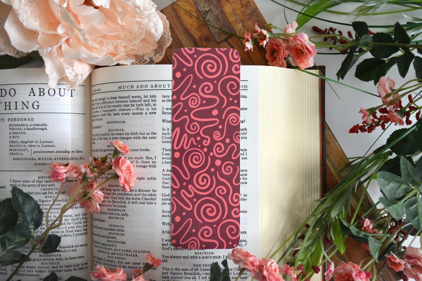 Bookmark with pink icing drizzle swirls on a maroon background.