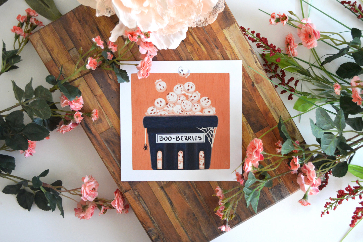 Halloween art print with illustration of boo-berries (ghost blueberries) in a blue punnet (basket), complete with spider and spider web on an orange textured background.