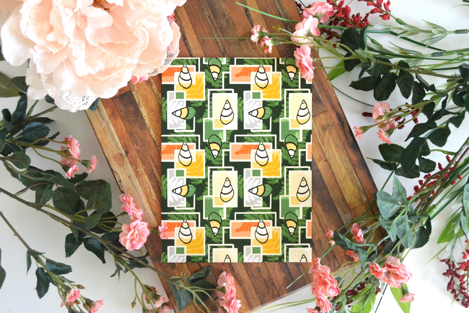 Greeting card with yellow, orange, and green kahuli (Hawaiian land snail) and fern geometric design on front.