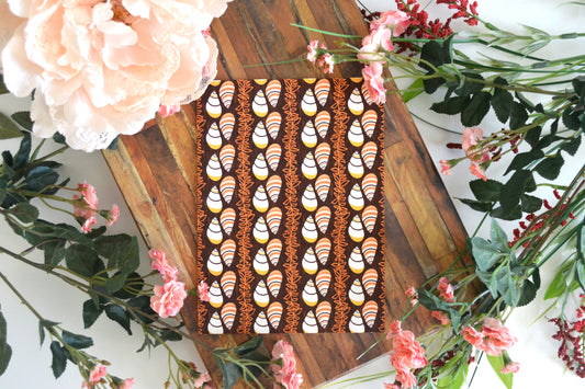 Greeting card with white, orange, yellow, and brown kahuli (Hawaiian land snail) and maile lei design on front.