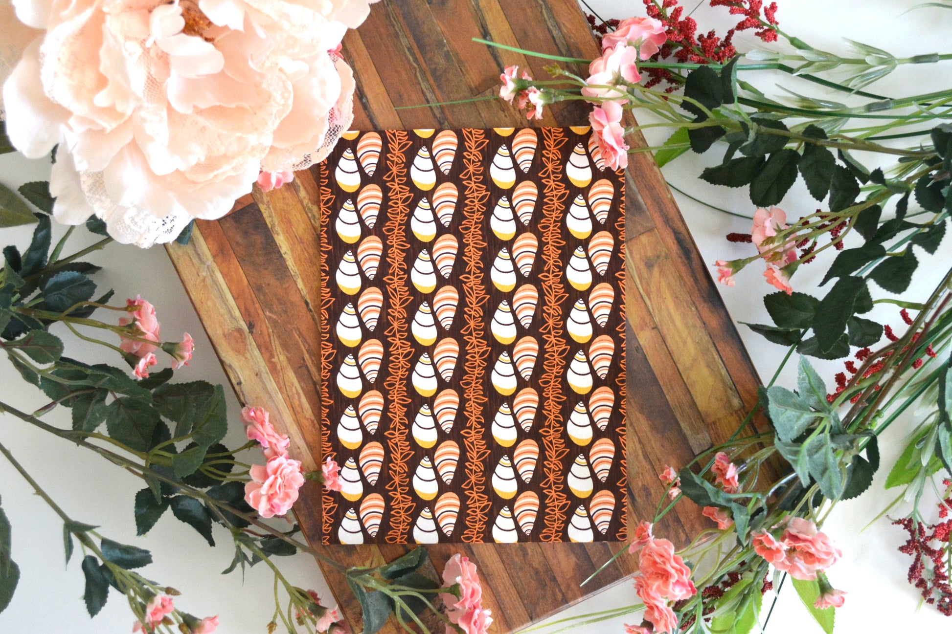 Greeting card with white, orange, yellow, and brown kahuli (Hawaiian land snail) and maile lei design on front.