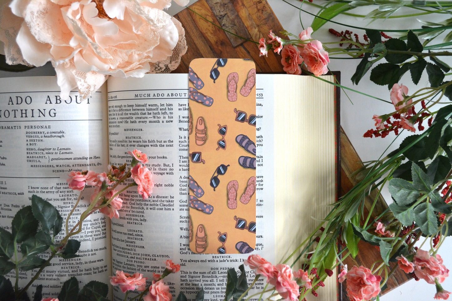 Bookmark with illustrations of sunglasses and slippers (flipflops) on a yellow sand background.