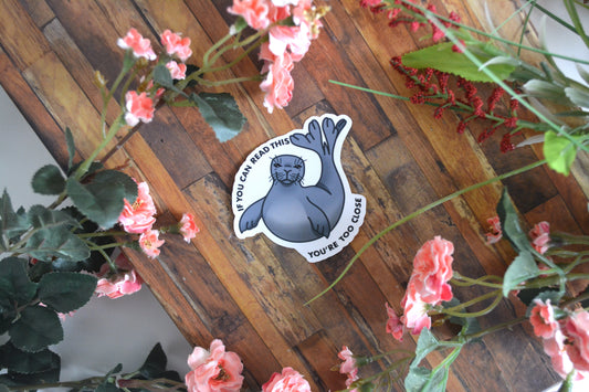 Individual sticker of a Hawaiian monk seal illustration with text reading "If you can read this you're too close" surrounding it.