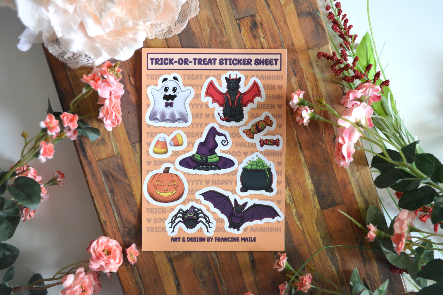 A glossy Halloween sticker sheet with 10 stickers on it, including a ghost, a cat with wings, candy, a cat under a witch's hat, a cauldron, a jack-o-lantern, a bat, and a spider.
